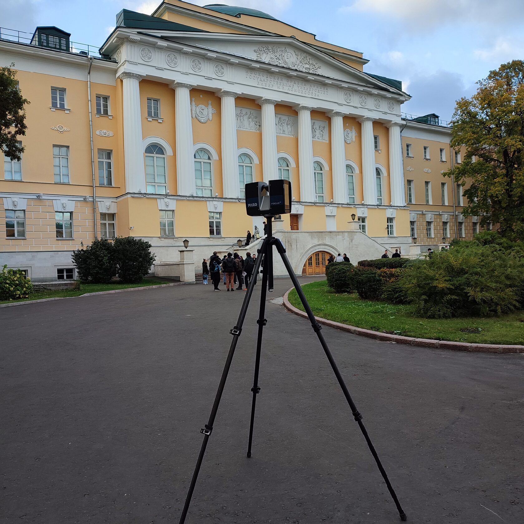 Лазерный сканер на штативе перед фасадом здания факультета МГУ во время полевой съёмки